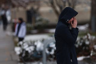 A person stand outside of the engineering and physics building where a shooter opened fire Saturday evening